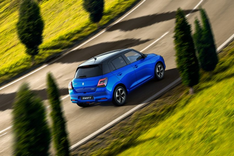 Suzuki Swift màu xanh chạy trên đường đèo