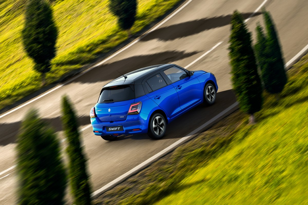 Suzuki Swift màu xanh chạy trên đường đèo