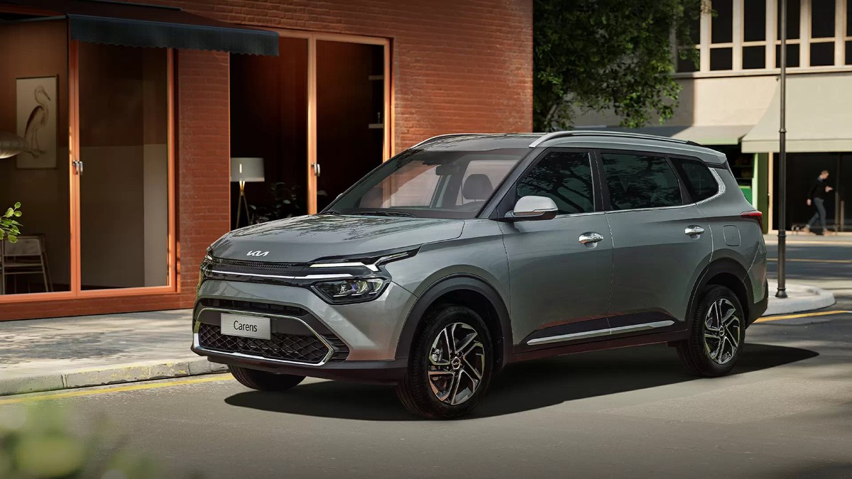 Kia Carens màu xám đỗ trước khu nhà gạch