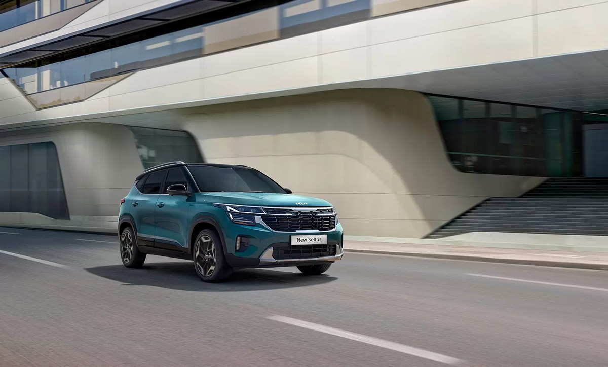 Kia New Seltos màu xanh chạy qua khu nhà hiện đại